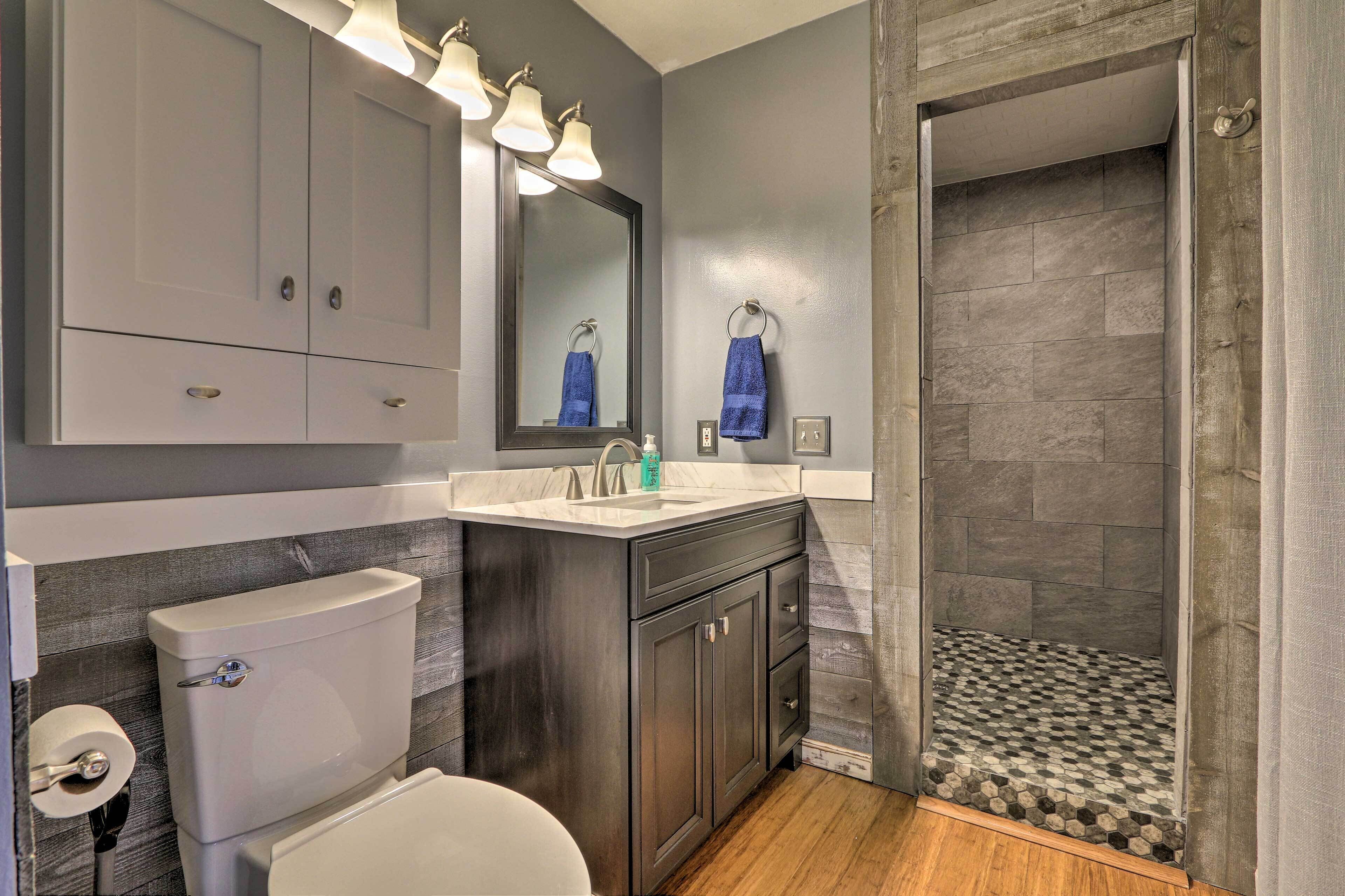 A bathroom with a toilet, sink, mirror, and shower area.
