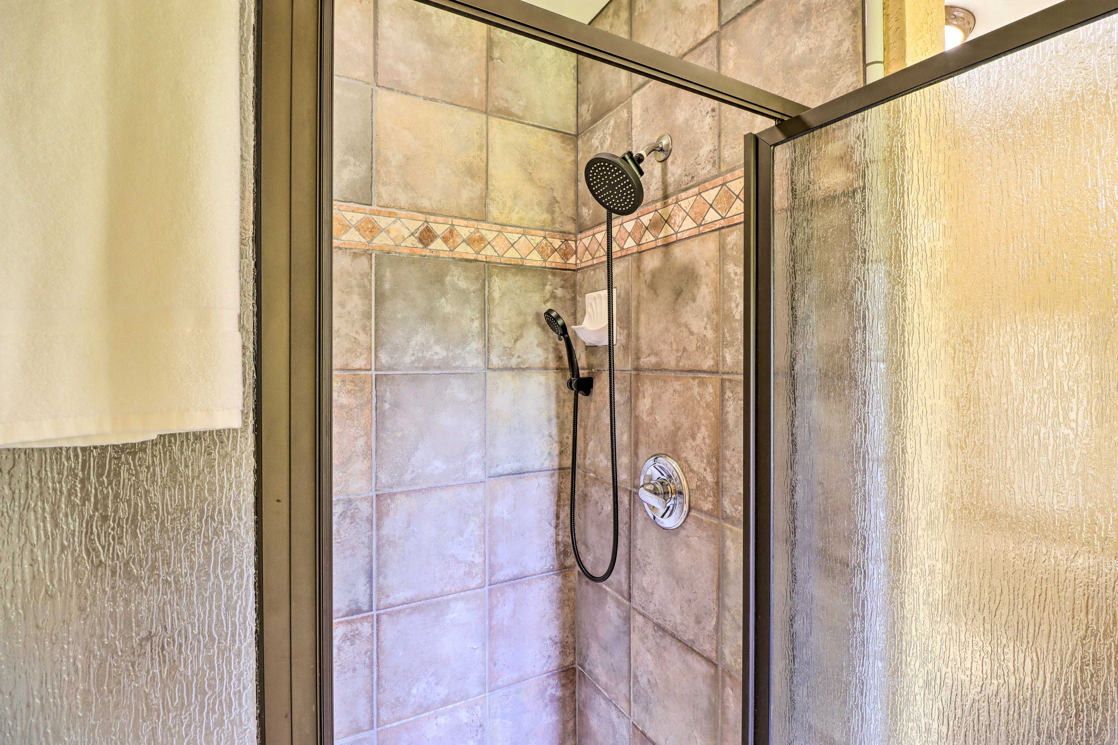 A shower with a handheld showerhead and a wall-mounted faucet.