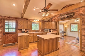 A rustic kitchen with wooden cabinets, a central island, and a ceiling fan. - Norfolk Lake Adventure Base! 3 Mi to Water, Deck (Mountain Home)