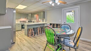 A modern kitchen with a central island, bar stools, and a dining table with colorful chairs. - Pet-friendly Waynesville Home w/ Mountain Views! (Waynesville)