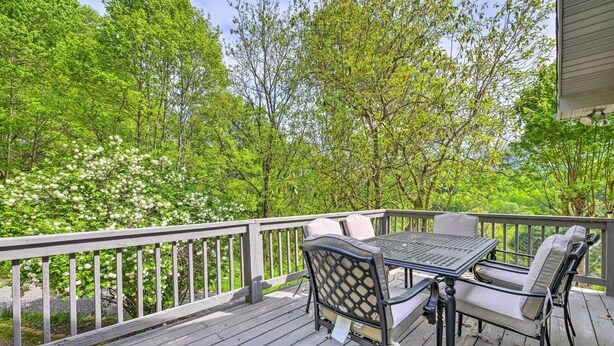 A wooden deck with a table and chairs, surrounded by lush green trees. - Pet-friendly Waynesville Home w/ Mountain Views! (Waynesville)