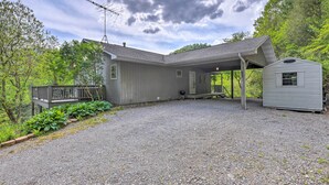 A two-story house with a covered porch, a small attached garage, and a gravel driveway. - Pet-friendly Waynesville Home w/ Mountain Views! (Waynesville)