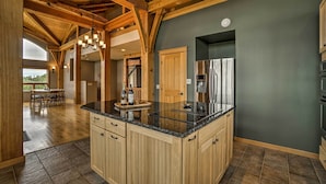 A spacious kitchen with wooden cabinets, a granite countertop, and a stainless steel refrigerator. - Home w/ Kachemak Bay View - 5 Miles to Downtown! (Homer)