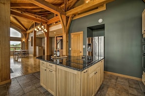 A spacious kitchen with wooden cabinets, a granite countertop, and a stainless steel refrigerator. - Home w/ Kachemak Bay View - 5 Miles to Downtown! (Homer)