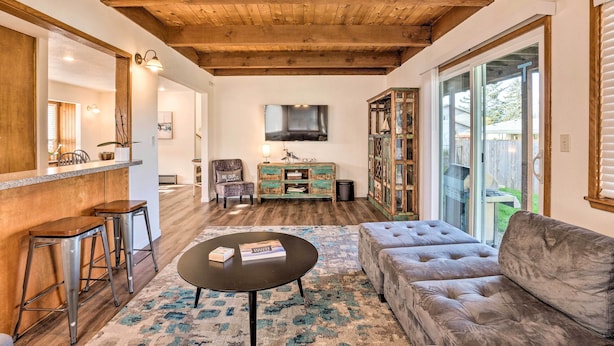 Un salon chaleureux avec un plafond en bois, un canapé, une table basse et un coin bar équipé de tabourets.