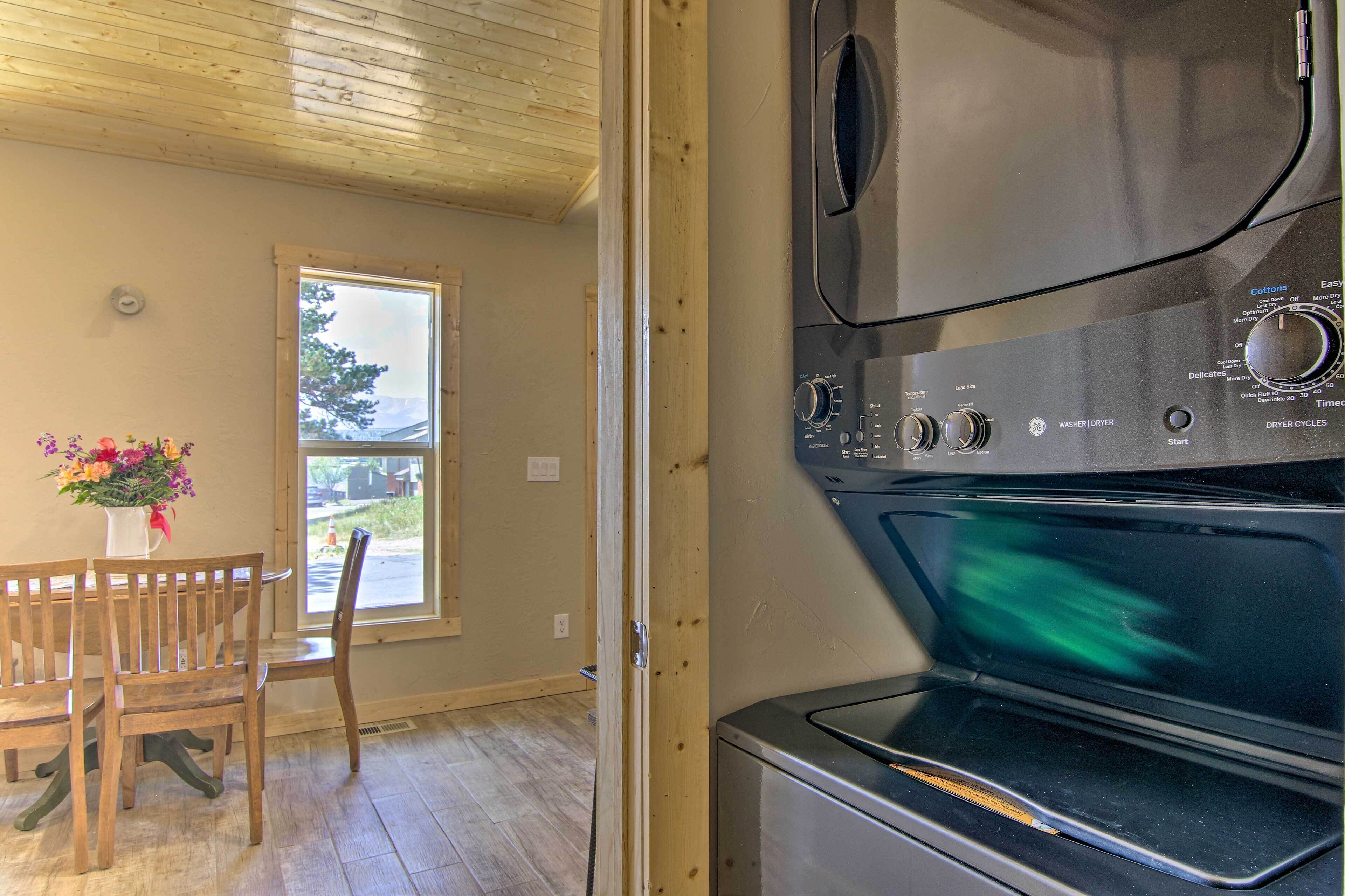 A room with a wooden ceiling, a window, a wooden table with chairs, and a washing machine.