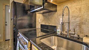 A modern kitchen with a stainless steel sink, black stove, and a range hood. - Mountain Cabin, Walk to Dining/memorial Park! (Woodland Park)