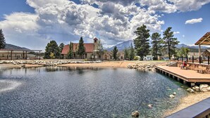 A serene lakeside setting with a building featuring a tower, surrounded by trees and a clear sky. - Mountain Cabin, Walk to Dining/memorial Park! (Woodland Park)
