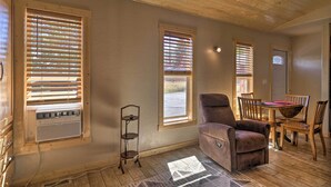 A room with a wooden ceiling, a brown leather chair, a dining table with chairs, and a window with blinds. - Mountain Cabin, Walk to Dining/memorial Park! (Woodland Park)