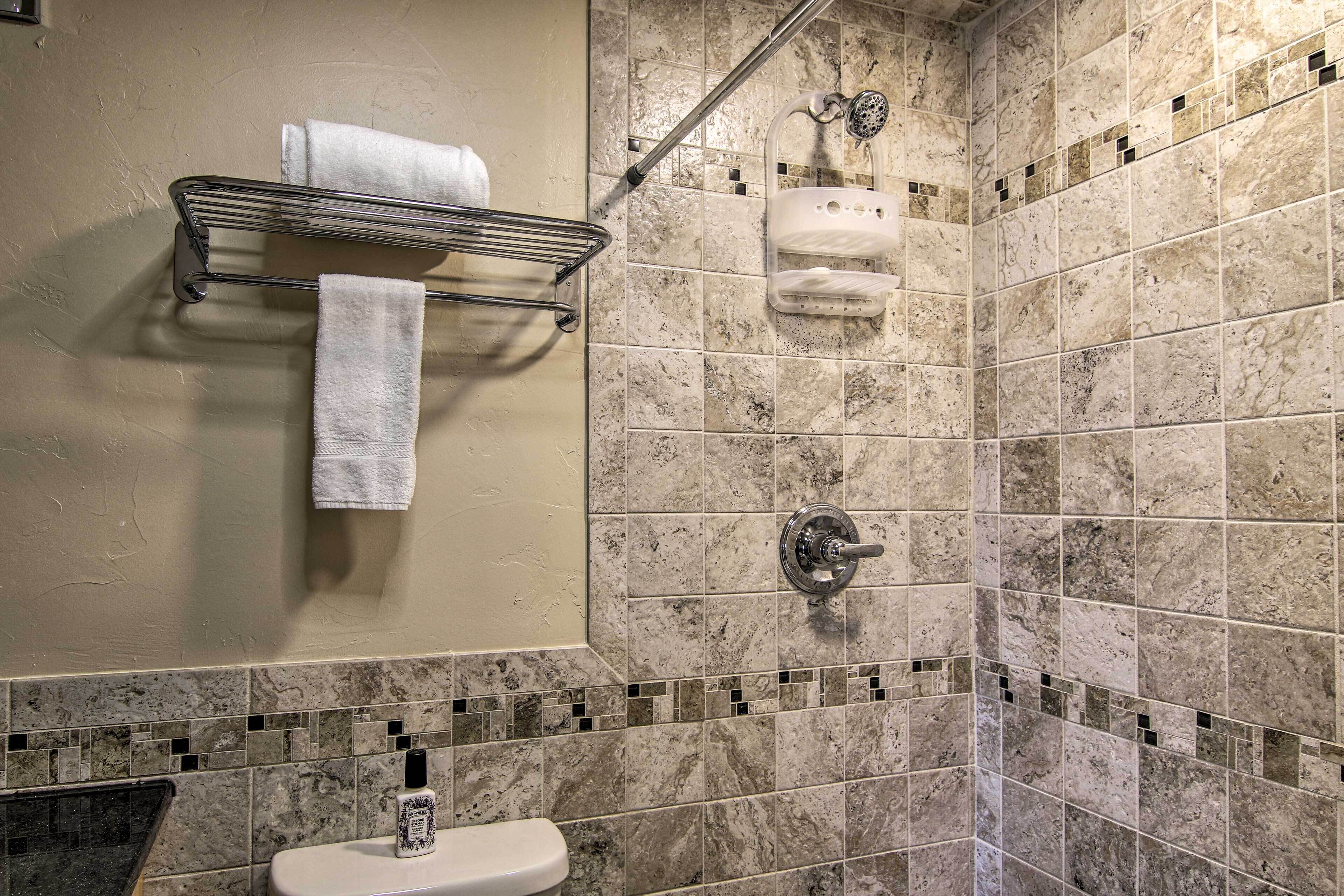 A bathroom with a shower, a toilet, and a towel rack.