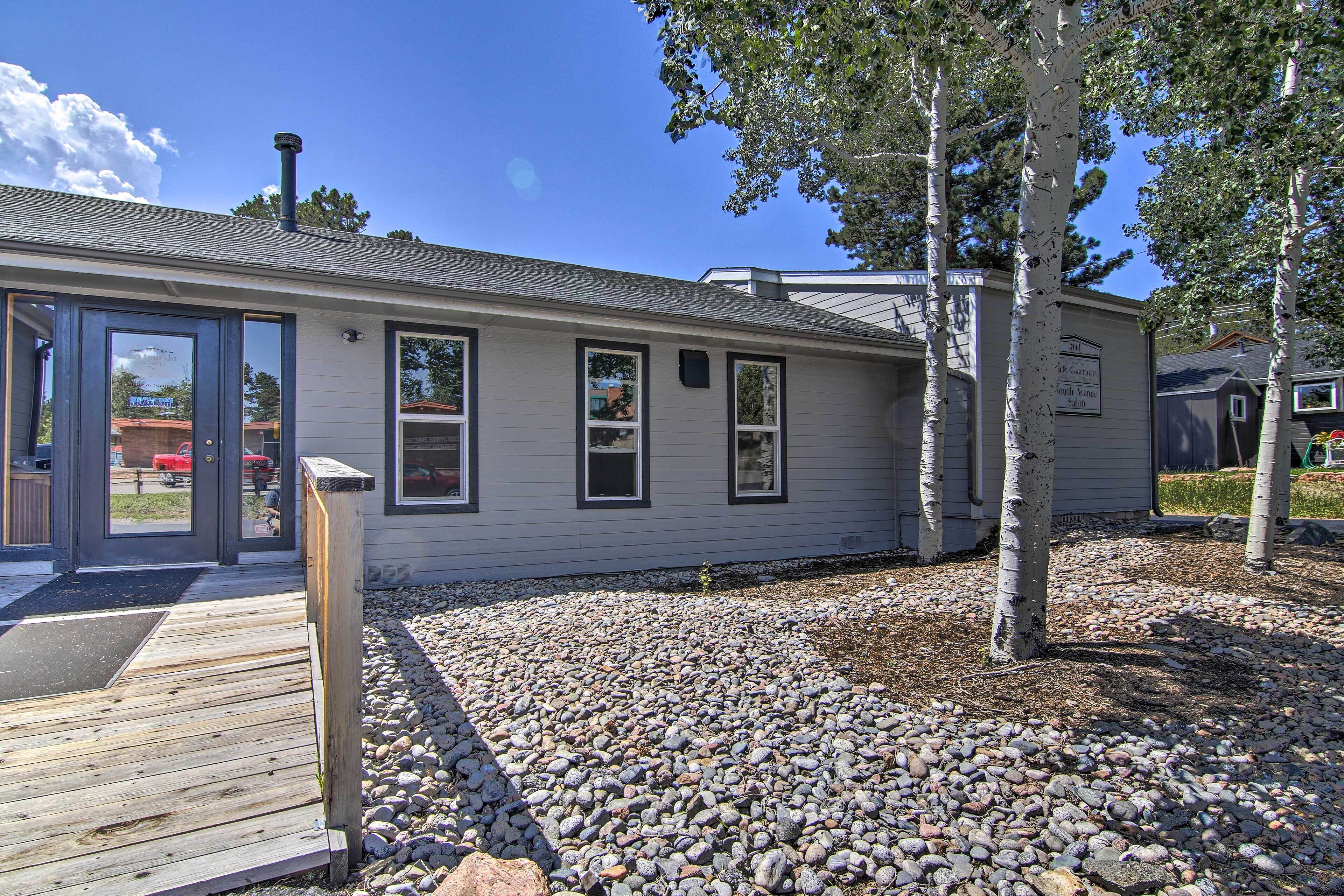 A single-story building with a wooden deck, a gravel driveway, and a sign indicating a rental property.