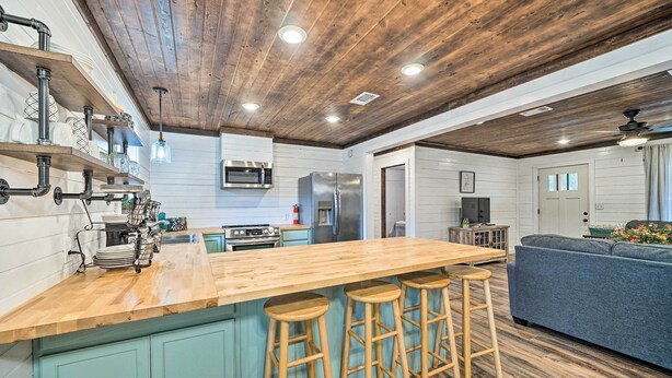 A kitchen with a wooden island, bar stools, a microwave, and a refrigerator. - Updated Family Home, 20 Mi to Broken Bow Lake! (Bethel)
