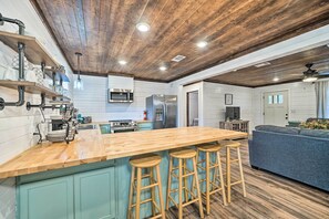A kitchen with a wooden island, bar stools, a microwave, and a refrigerator. - Updated Family Home, 20 Mi to Broken Bow Lake! (Bethel)