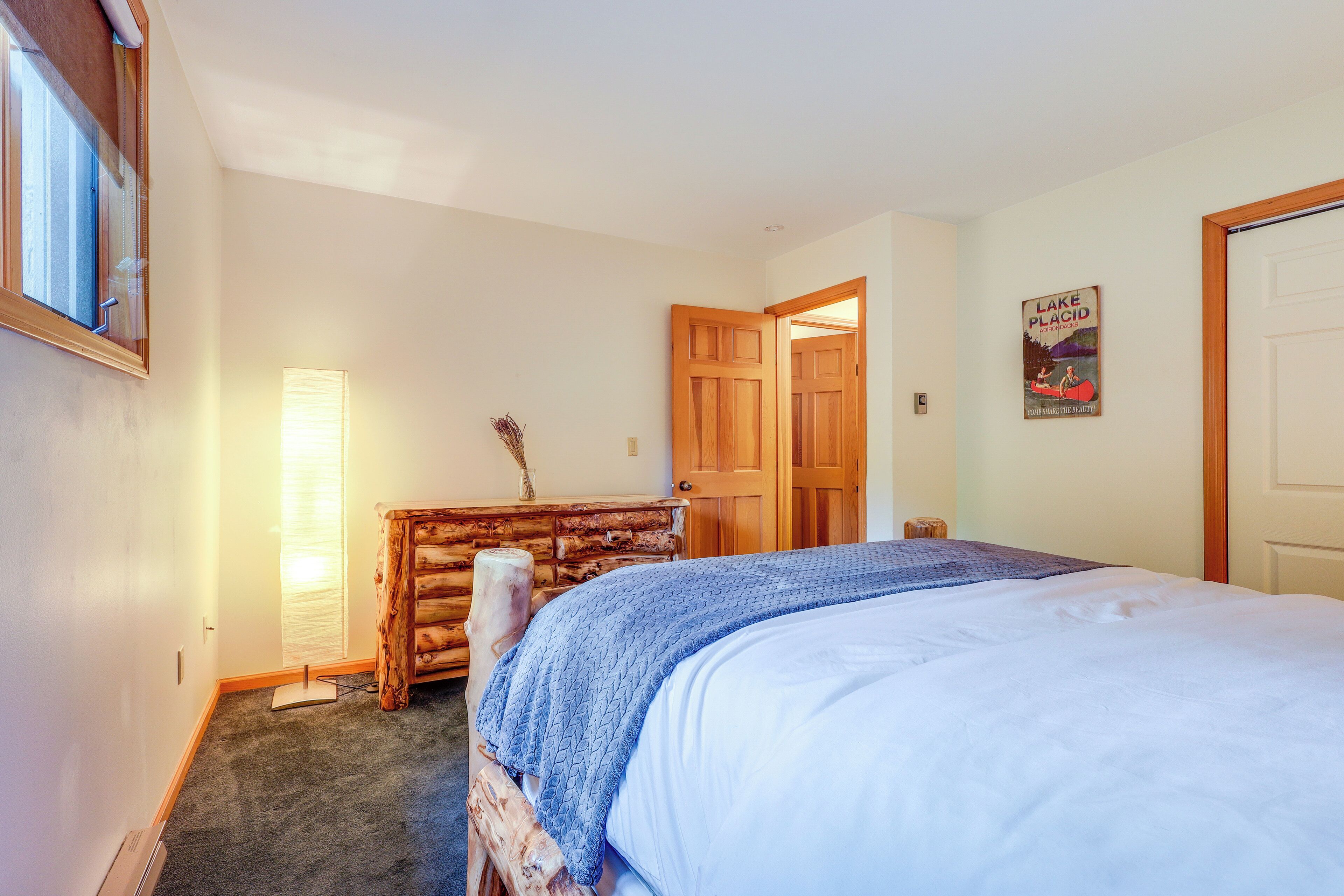 Un dormitorio con cama, cómoda de madera y puerta que da a otra habitación.