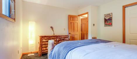 Un dormitorio con cama, cómoda de madera y puerta que da a otra habitación.