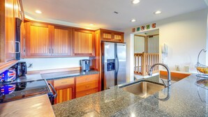 A modern kitchen with wooden cabinets, stainless steel appliances, granite countertops, and a built-in oven.