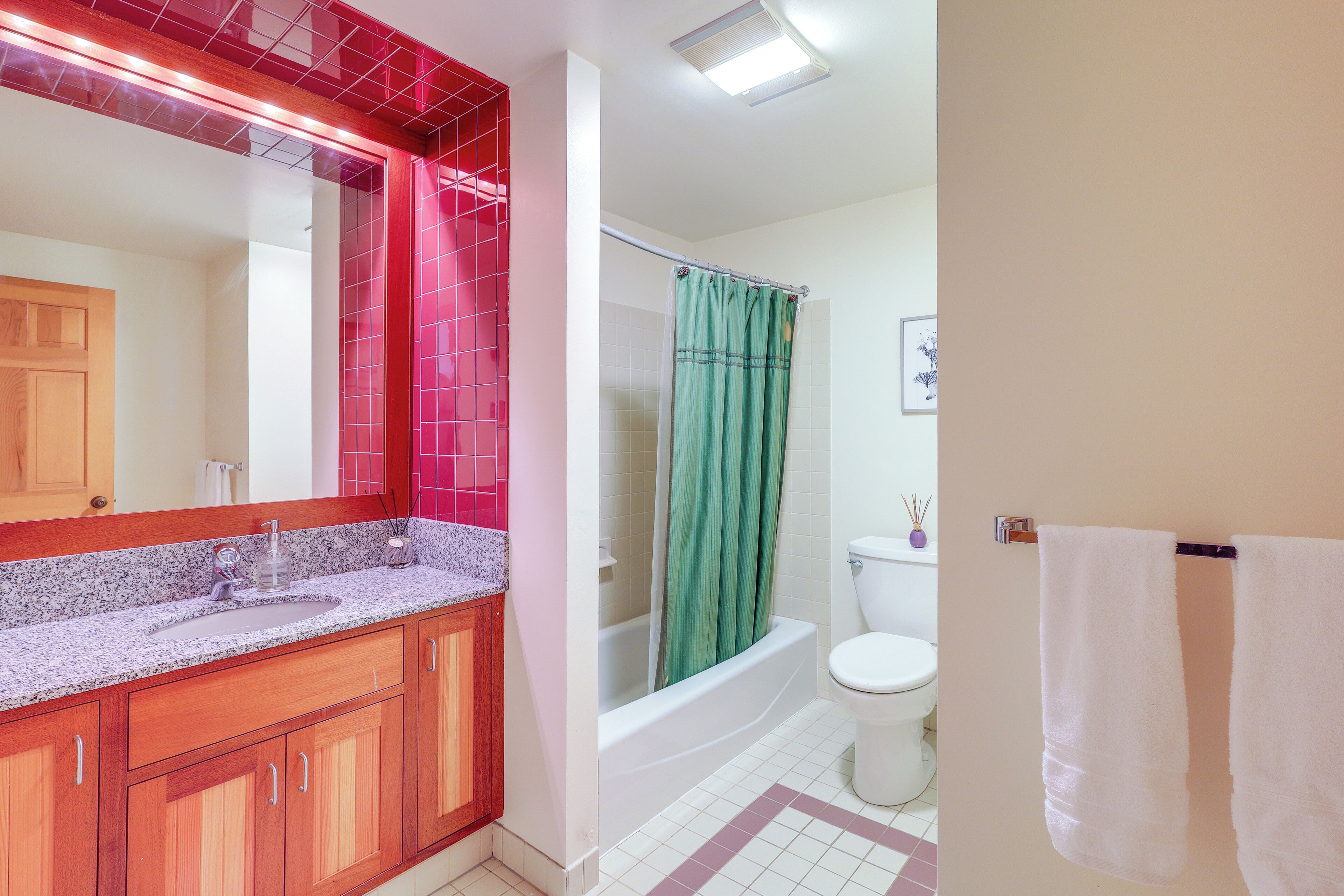 A bathroom with a wooden vanity, a sink, a mirror, a bathtub, and a toilet.