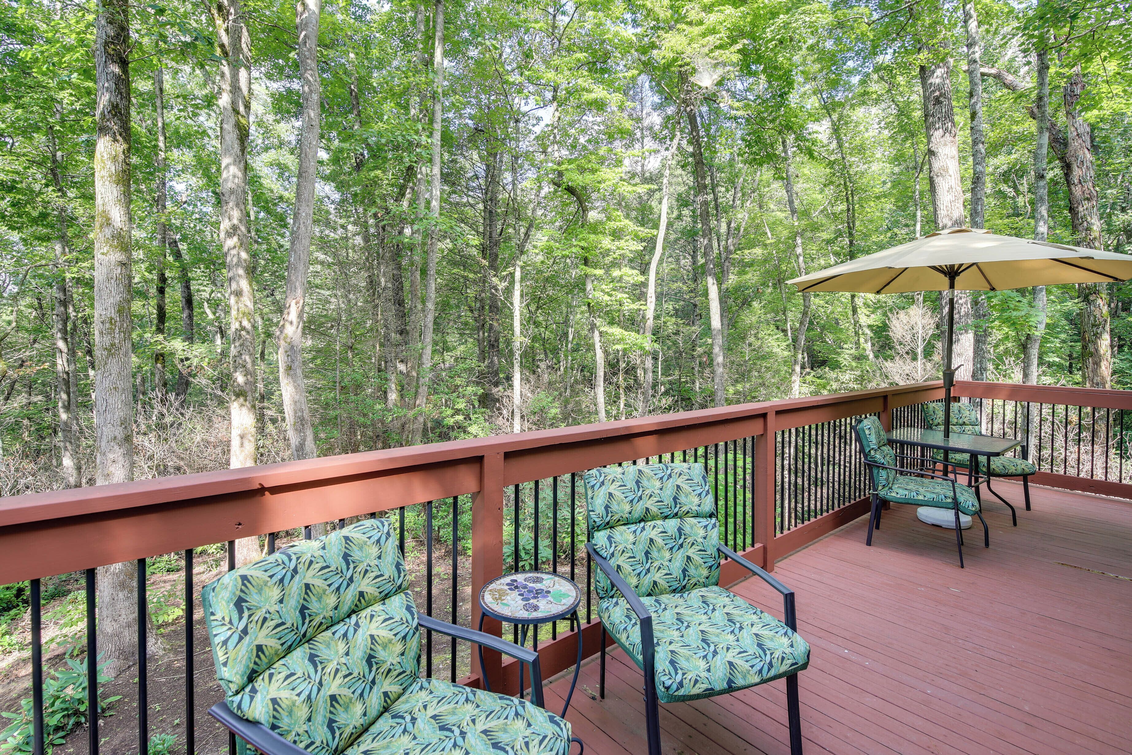 Une terrasse dotée de mobilier d’extérieur, comprenant des chaises et une table, et entourée d’une rambarde en bois.