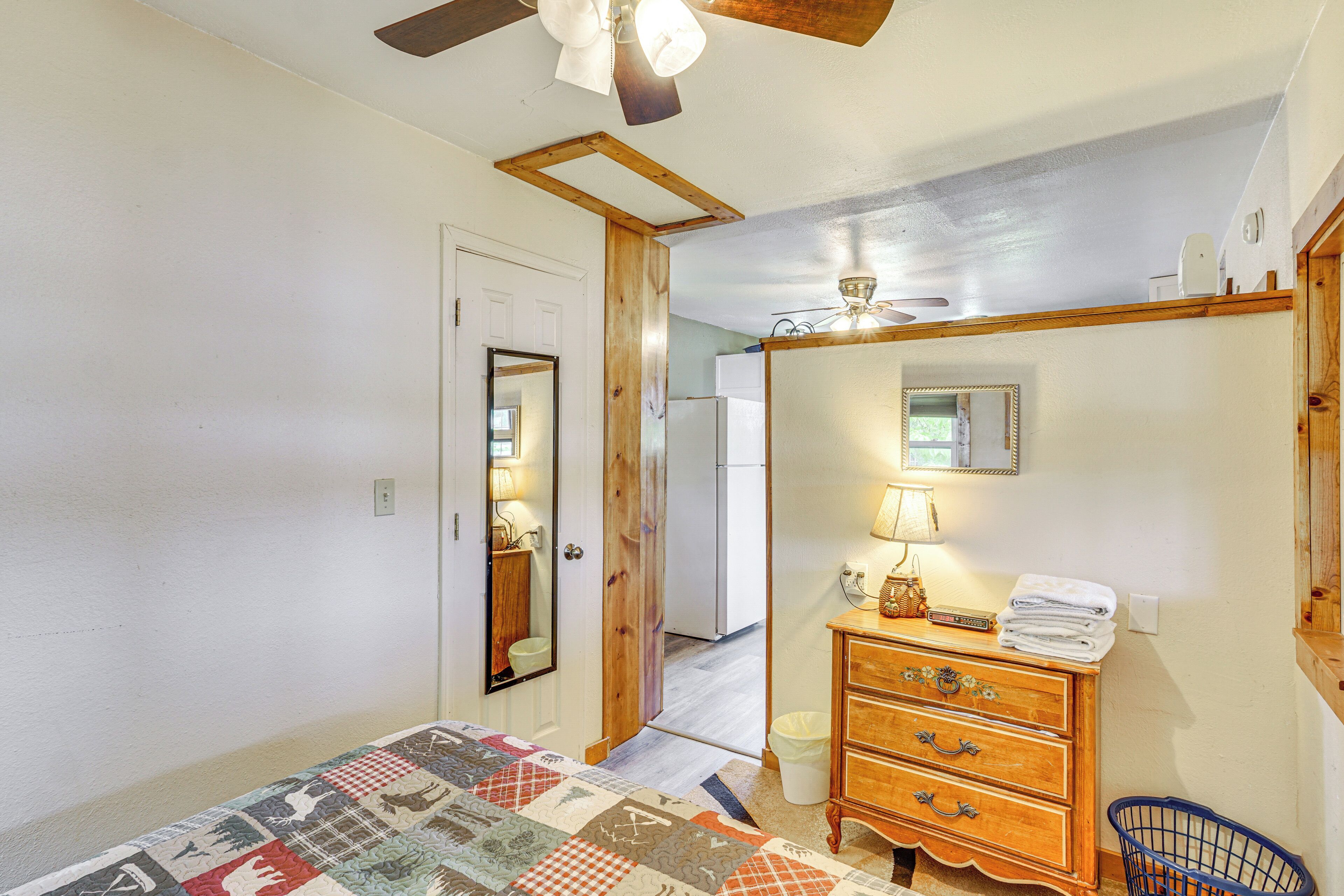 Um quarto com uma cama, cômoda, espelho e ventilador de teto.