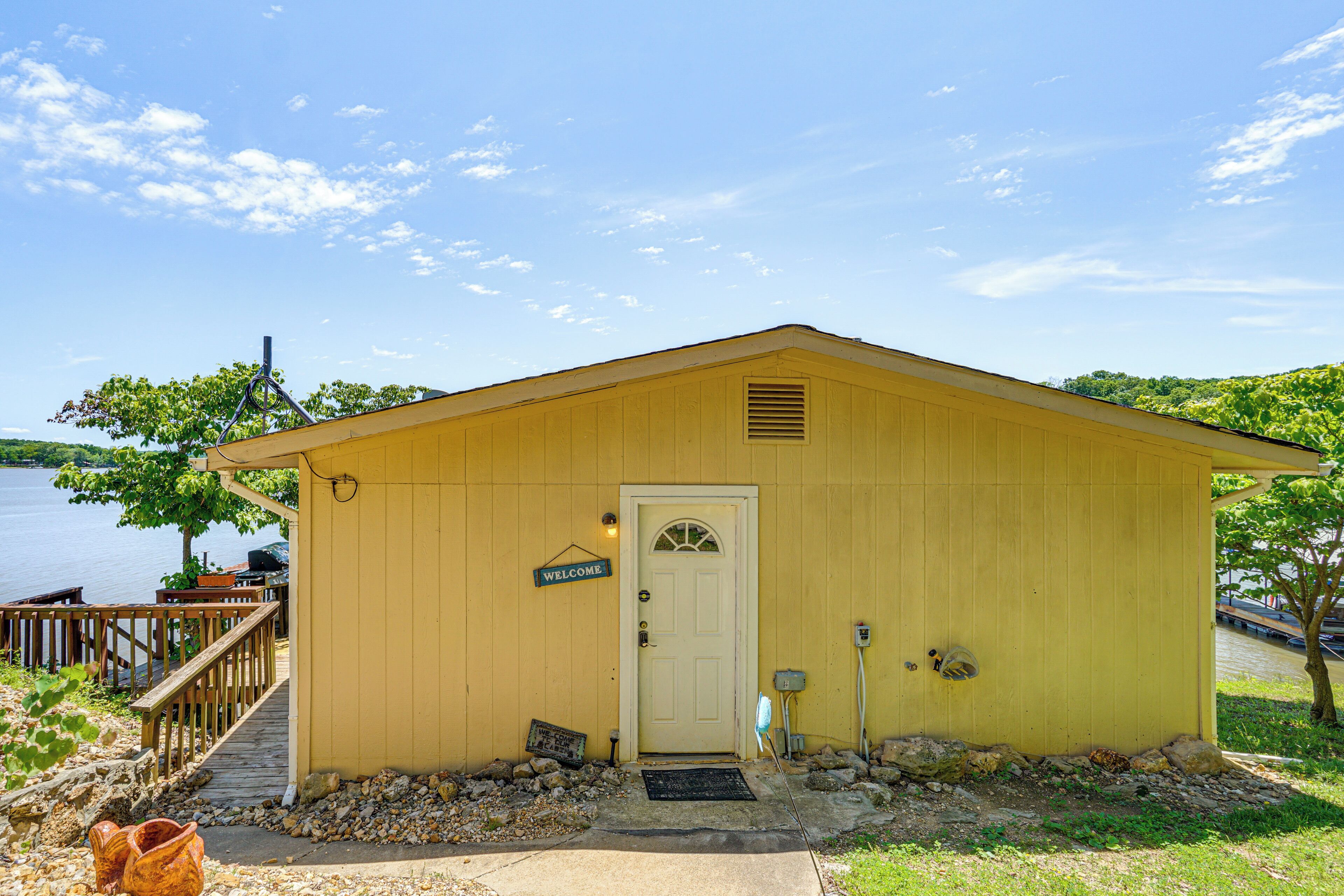 A yellow building with a white door, a welcome sign, and a small porch.