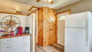 A compact kitchen with wooden cabinets, a white refrigerator, and a ceiling fan. - Deck w/ Covered Dock! Lakefront Ozark Cottage (Climax Springs)