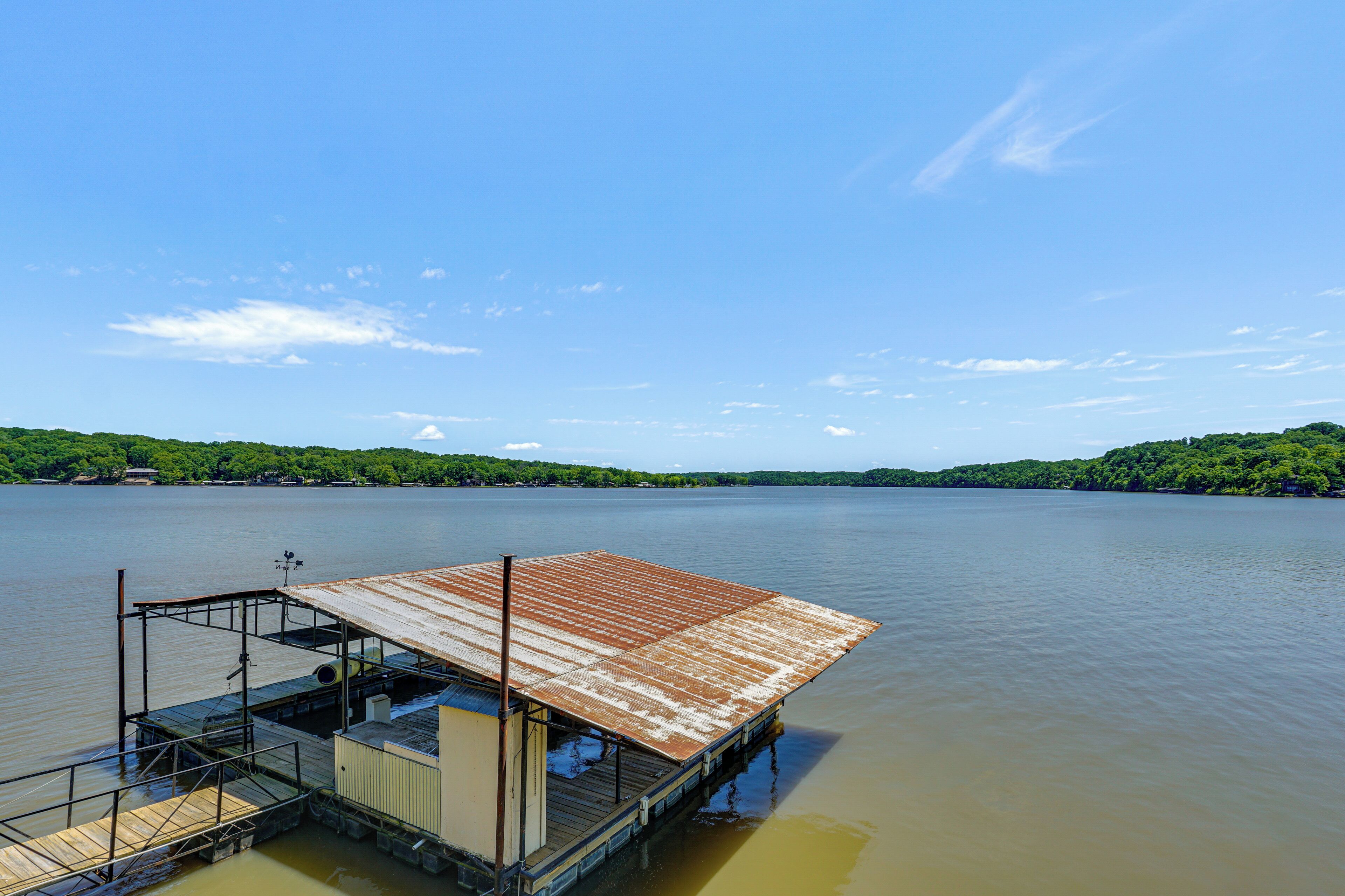 A dock extending into a calm lake with a clear sky.