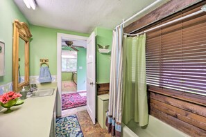 A bathroom with a green wall, a wooden vanity, a sink with a mirror, and a shower with a wooden window blind. - Furnished Deck + Home Gym: Bakersville Retreat! (Bakersville)