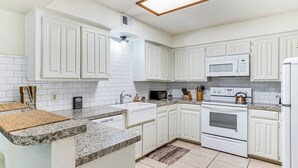 A kitchen with white cabinets, a granite countertop, a microwave, a stove, and a sink. - 4 Mi to At&t Stadium: Fort Worth Townhome! (Fort Worth)