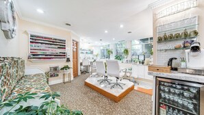 A salon interior with a patterned sofa, a coffee table, and a wall of hair products. - Experience Chautauqua! Newly Renovated Studio (Mayville)