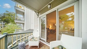 A covered porch with wicker furniture, a small round table, and a view into the house. - Experience Chautauqua! Newly Renovated Studio (Mayville)