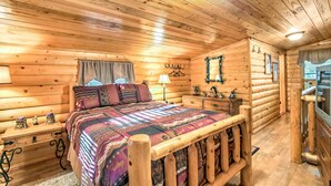 A log cabin bedroom with a wooden bed, a nightstand, a dresser, and a mirror. - Porch & Fire Pit: Rustic Log Cabin in Smokies! (Cosby)