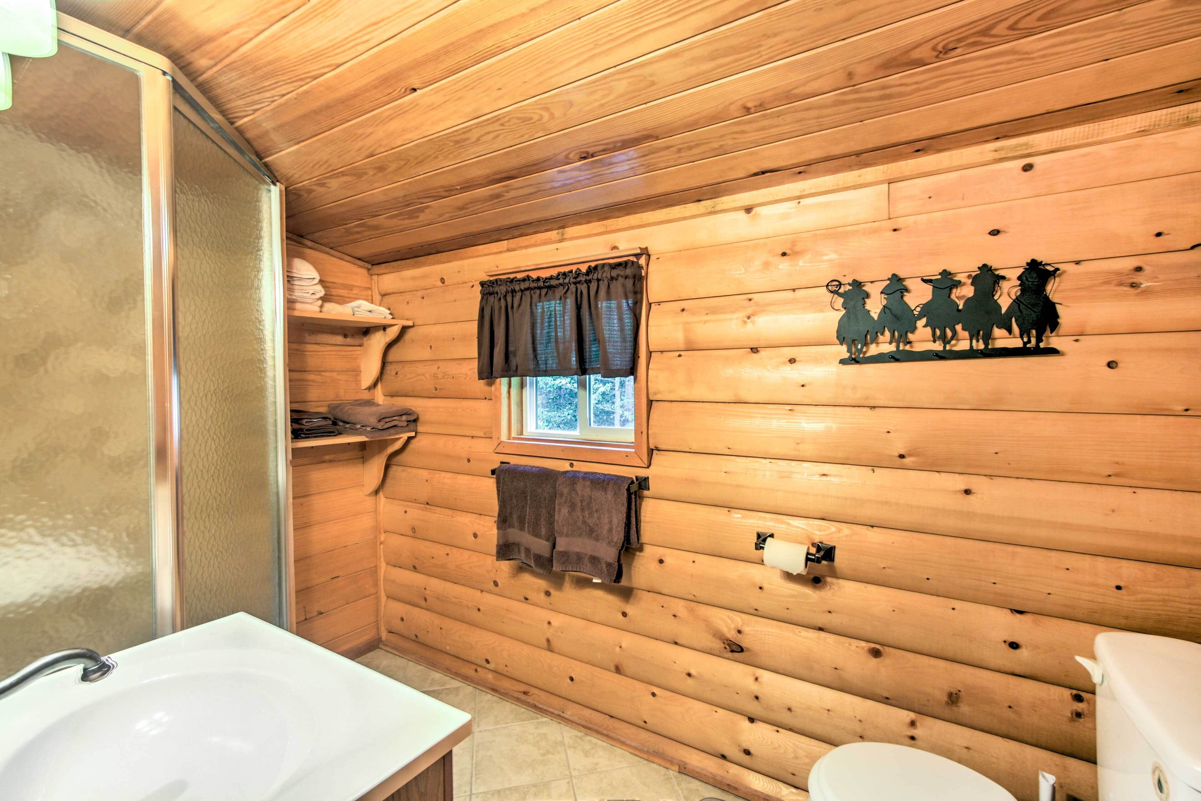 Un baño rústico con cabaña, que incluye un lavamanos, un inodoro y una ventana con cortinas.
