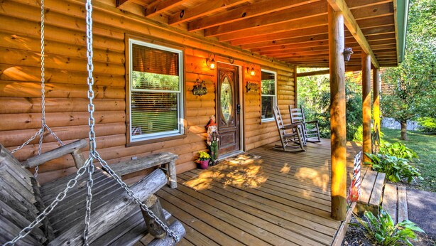 A wooden cabin with a porch, a swing, and a door with a 'Welcome' sign. - Porch & Fire Pit: Rustic Log Cabin in Smokies! (Cosby)