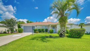 A single-story house with a garage, surrounded by well-maintained grass and palm trees. - Home in The Villages w/ Lanai & Private Hot Tub! (The Villages)