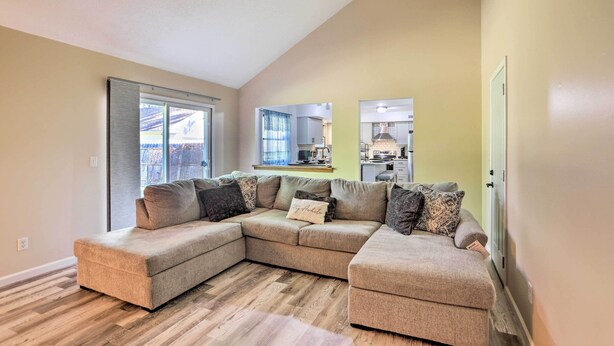 A modern living room with a sectional sofa, a dining area, and a kitchen in the background.