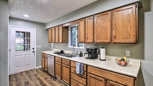 A kitchen with wooden cabinets, a white countertop, a dishwasher, and a window. - Peaceful Cottage w/ Mtn View Near ATV Trails! (Welch)