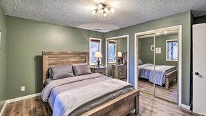 A bedroom with a wooden bed, a ceiling fan, and a large mirror. - Peaceful Cottage w/ Mtn View Near ATV Trails! (Welch)
