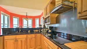 A kitchen with wooden cabinets, a black countertop, and a stainless steel range hood. - Charming Waterfront Home: Fish, Boat + More! (Sneads Ferry)