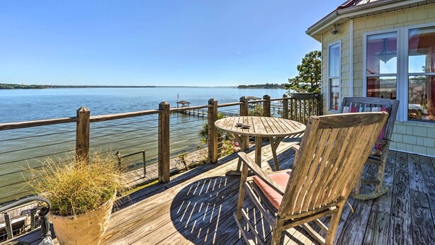 A wooden deck with a table and chairs overlooking a calm body of water. - Charming Waterfront Home: Fish, Boat + More! (Sneads Ferry)