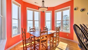 A dining area with a wooden table and chairs, large windows, and a view of the water. - Charming Waterfront Home: Fish, Boat + More! (Sneads Ferry)