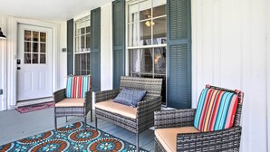 A porch with wicker chairs, a patterned rug, and a white door. - Pet-friendly Surfside Beach Home w/ Deck & Grill (Freeport)