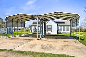 A covered outdoor area with a concrete floor, metal roof, and a small building with windows and a door. - Pet-friendly Surfside Beach Home w/ Deck & Grill (Freeport)