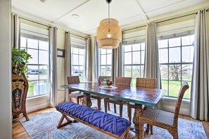 A dining area with a large wooden table, wicker chairs, and a bench. There is a hanging light fixture above the table. - Pet-friendly Surfside Beach Home w/ Deck & Grill (Freeport)