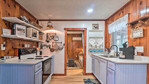 A kitchen with wooden walls, a stove, and cabinets. There is a sign on the wall and a window with blinds. - Cozy Knoxville Getaway ~ 8 Mi to Downtown! (Knoxville)