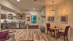 Une cuisine moderne dotée d’appareils électroménagers intégrés, un coin repas avec une table en bois et des chaises violettes, et un ventilateur de plafond.