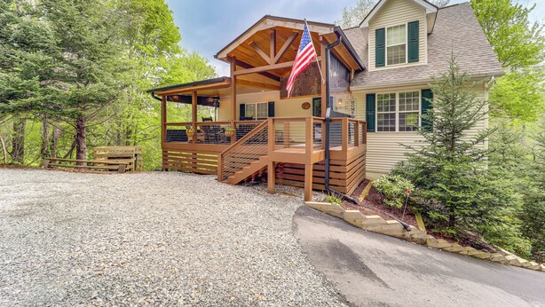 Eine zweistöckige Lodge mit überdachter Veranda, einer Flagge und einer Schotterauffahrt.