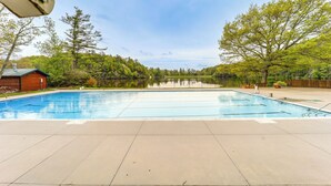Ein rechteckiger Pool mit glasklarer, blauer Wasseroberfläche, umgeben von einer gepflasterten Liegefläche.