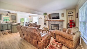 Ein geräumiges Wohnzimmer mit Ledersofas, einem Kamin und einer Küche im Hintergrund.