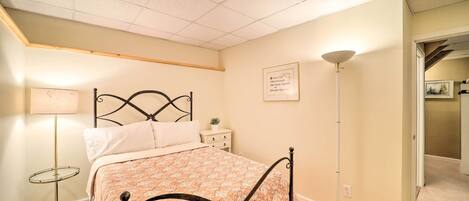 A bedroom with a bed, bedside table, lamp, and a framed certificate on the wall.