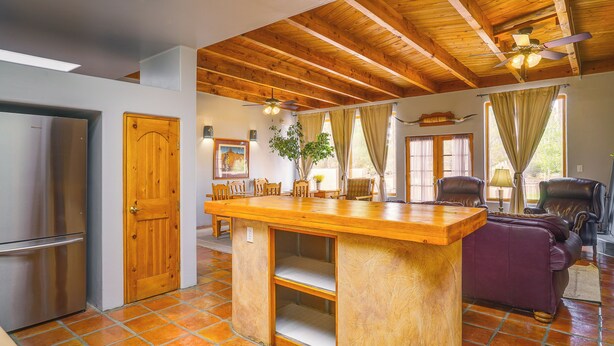 A spacious kitchen with a wooden ceiling and a central island, a refrigerator, and a dining area with chairs. - Las Cruces Adobe Near Mesilla & Nmsu (Las Cruces)